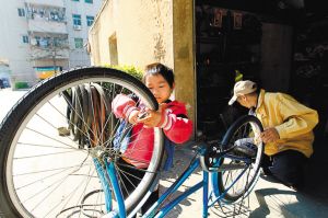 小樂怡與患癌癥的父親一同在店鋪修單車。